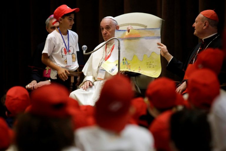 Papa Francesco con un salvagente in mano per spiegare chi sono i migranti